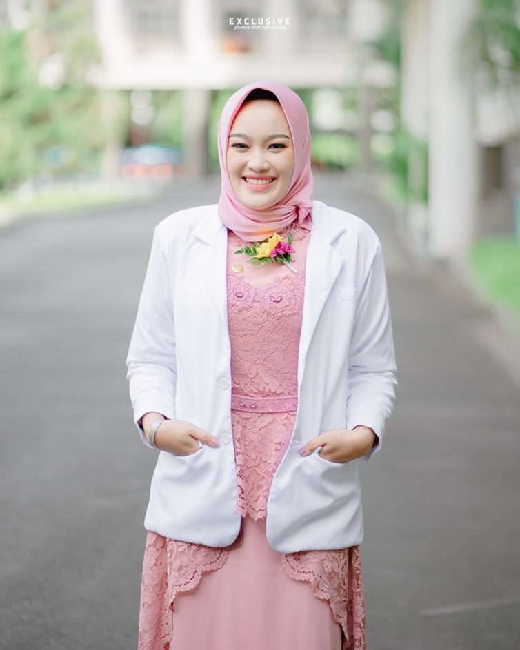 Person wearing lab coat posing outside.