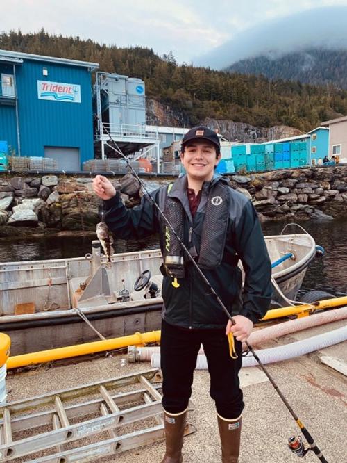 Person posing outside holding a fish they caught.