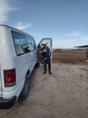 Person giving thumbs up and posing by van.