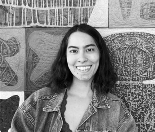 Person smiling in front of art.