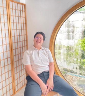 Person smiling in front of window.