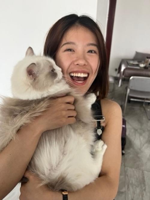 Person smiling and holding a cat.