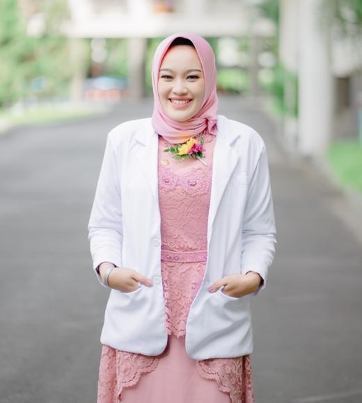 Person wearing lab coat posing outside.