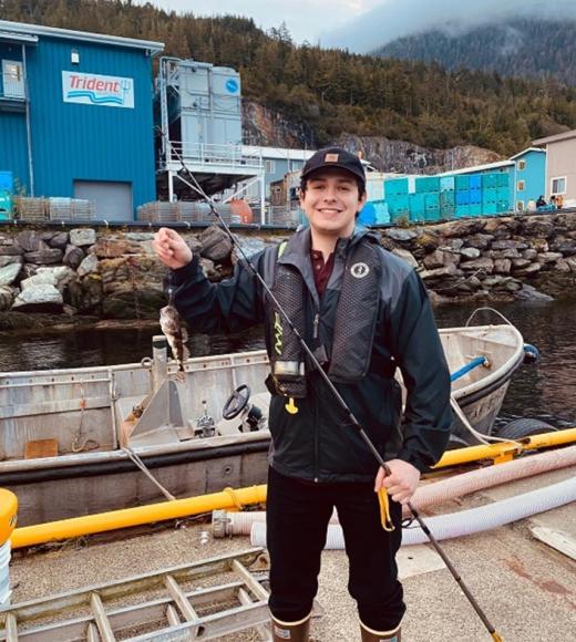 Person posing outside holding a fish they caught.
