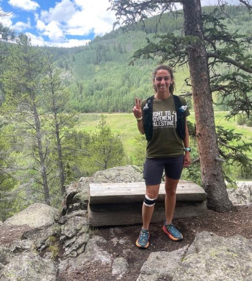 Person posing in front of mountain and trees.