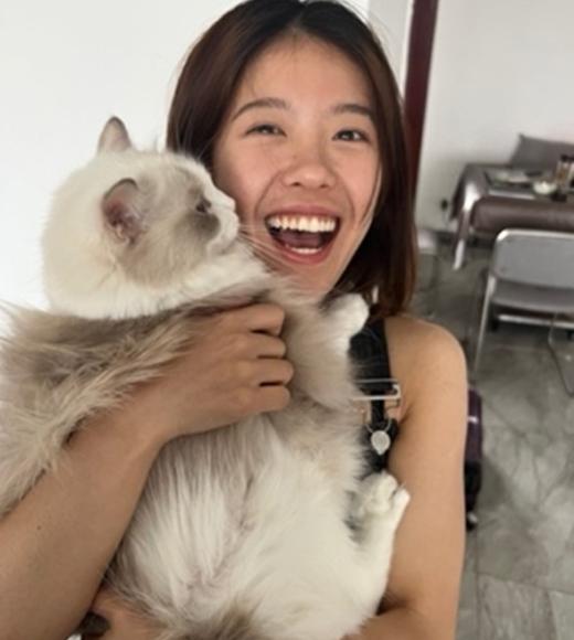 Person smiling and holding a cat.