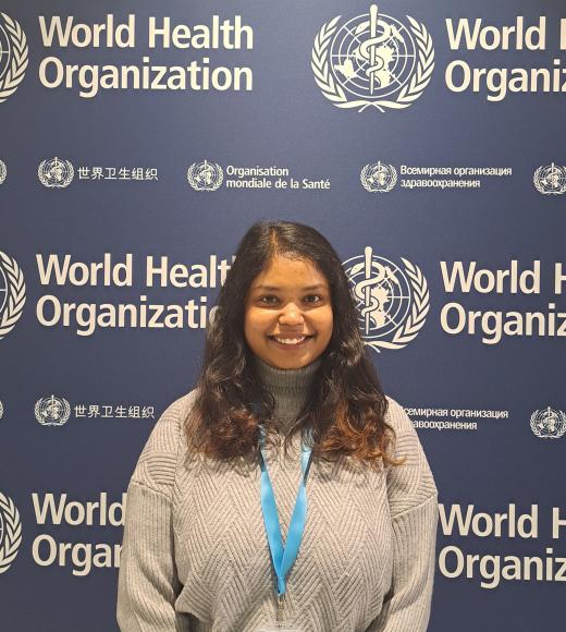 Jahnavi Akula stands in front of a banner with World Health Organization branding